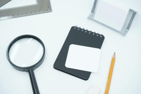 image of magnifying glass, pocket notebook, and pencil 