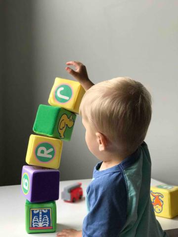 little boy stacking blocks about to tip over