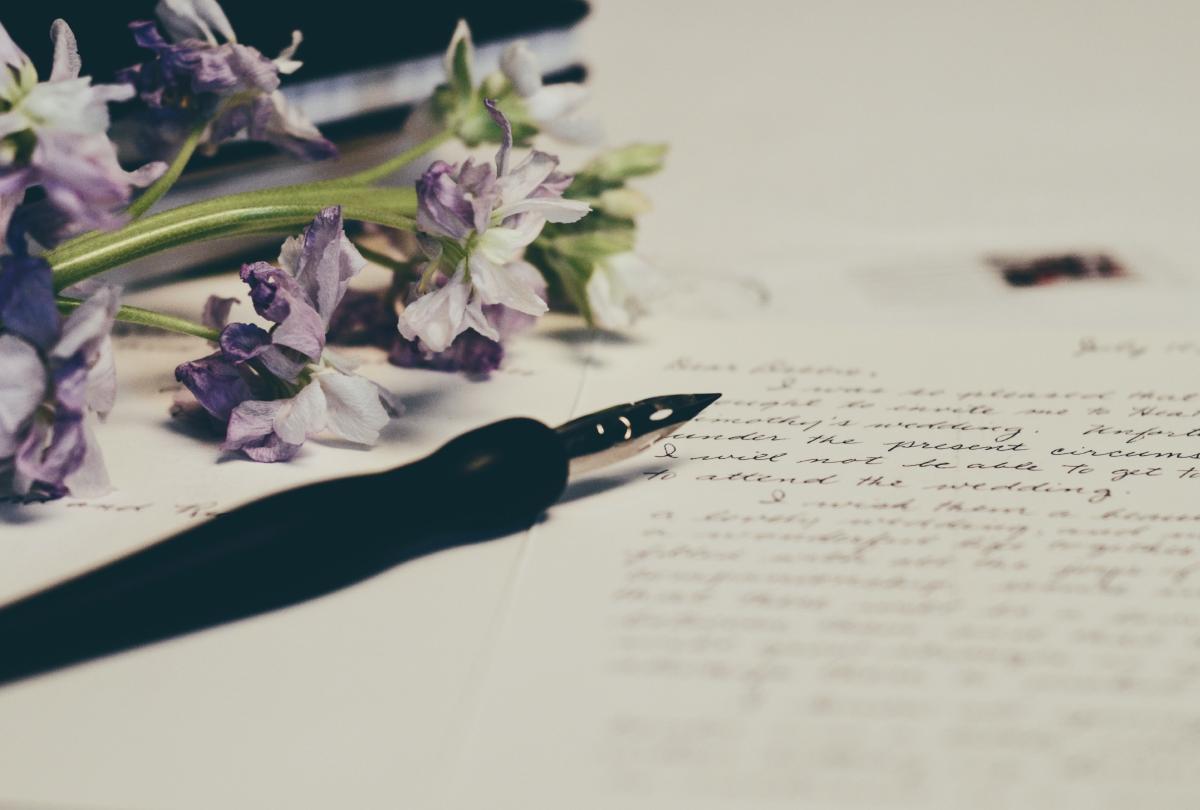 fountain pen cursive script on paper with wildflowers at edge of page