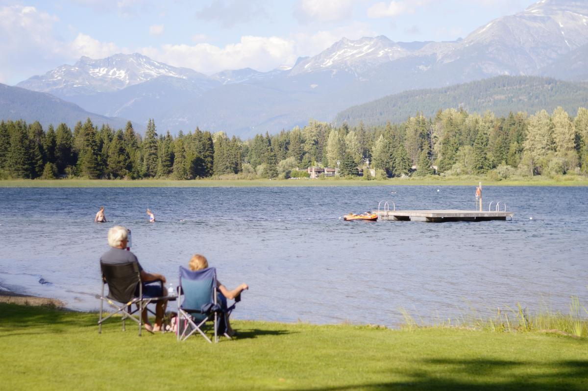 image of seniors sitting in folding chairs at the side of a lake 